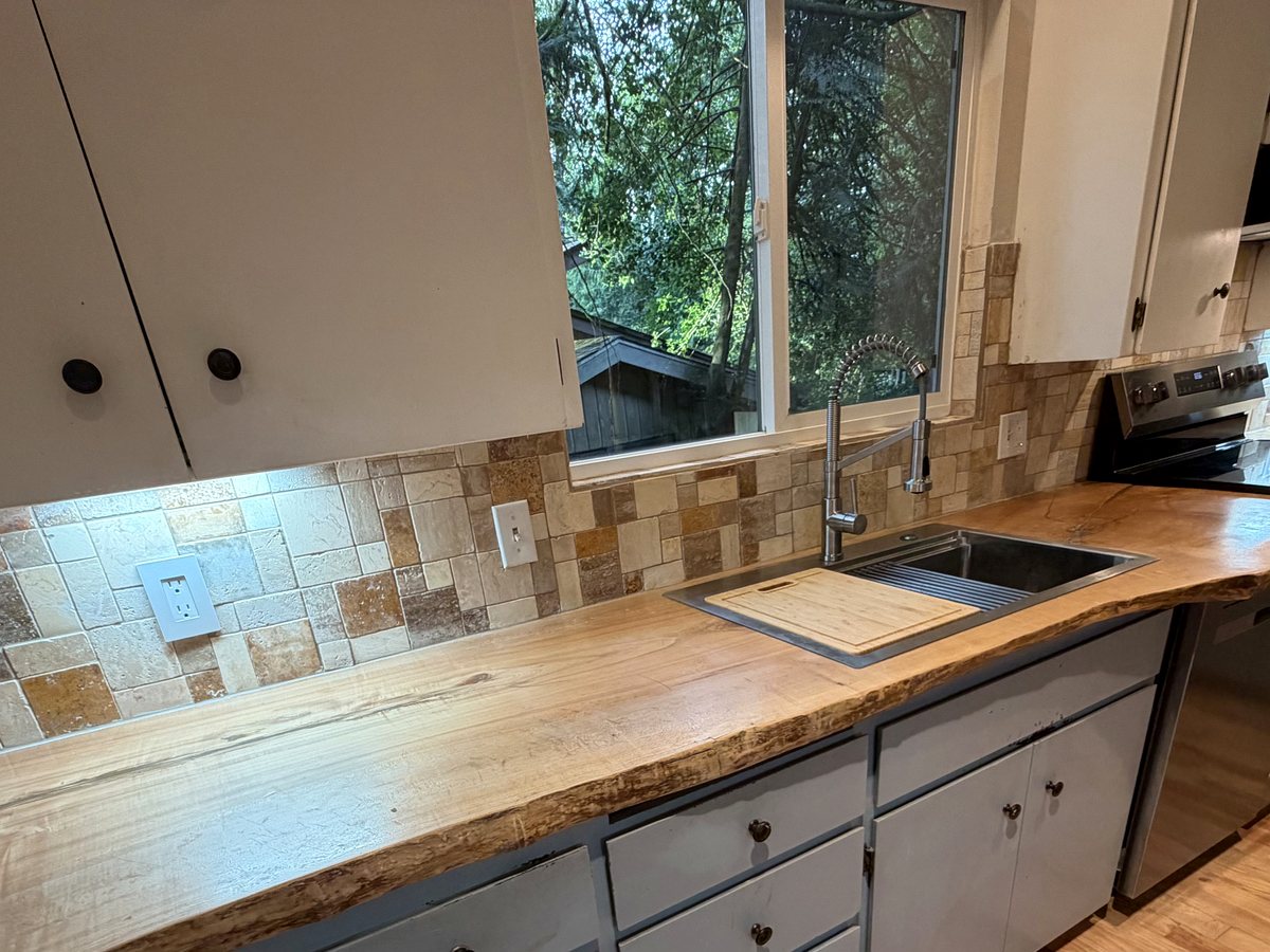 Live-edge wood countertop fitted around kitchen sink and window